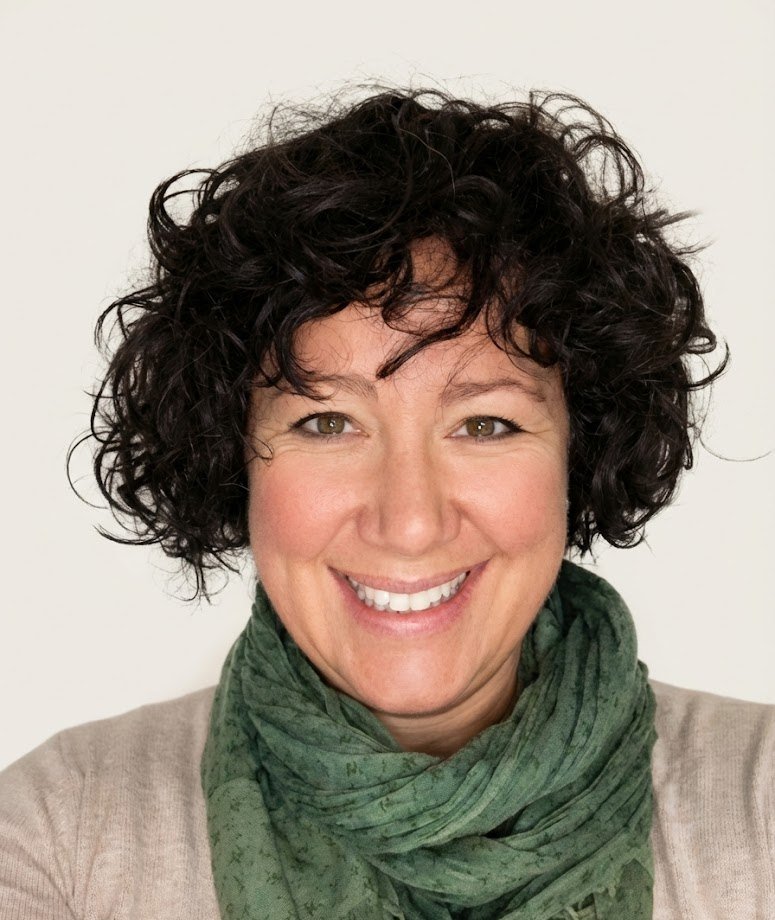 Portrait of Anne Frew, smiling, wearing a green scarf